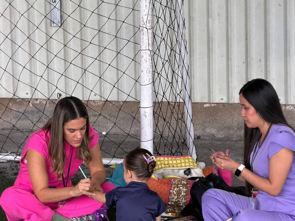 Doctoras de R&V Dental haciendo pintacaritas a un niño durante el taller en el preescolar